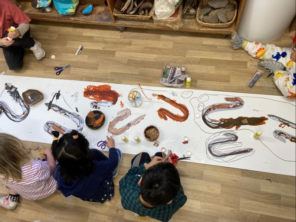 Children painting together on long paper