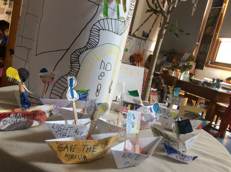 A photo of a children's art project, featuring boats made out of paper.