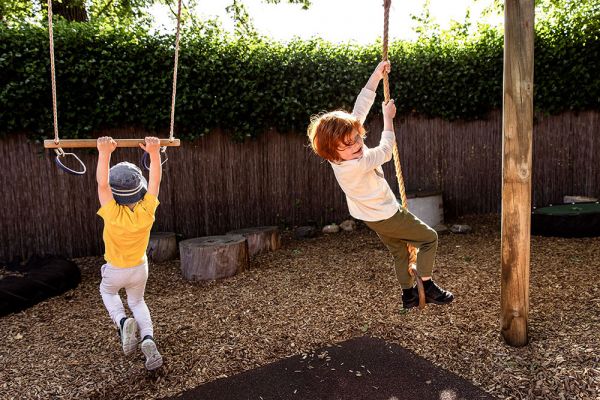 Two children playing on some swings