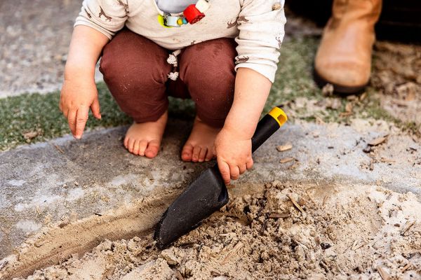A child playing with a shovel in the sandpit